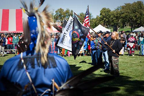 Several men hold Omaha Tribe flags on the Fort Omaha Fairgrounds